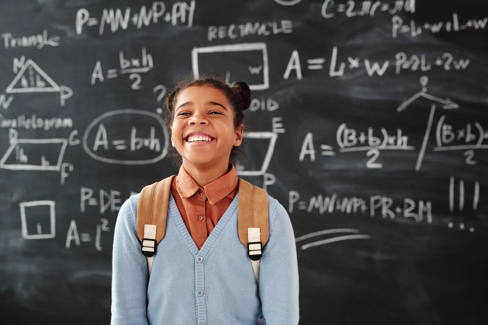 Aluna sorrindo em frente ao quadro da escola